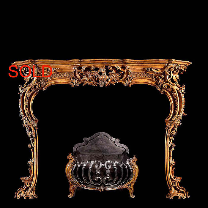 An antique carved pine Georgian Rococo fireplace surround     